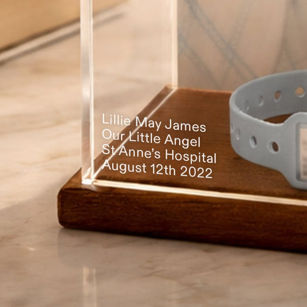 Clear baby memory case with photo of a baby and hospital bracelet on a marble surface, with 'Bright Ivy' branding.