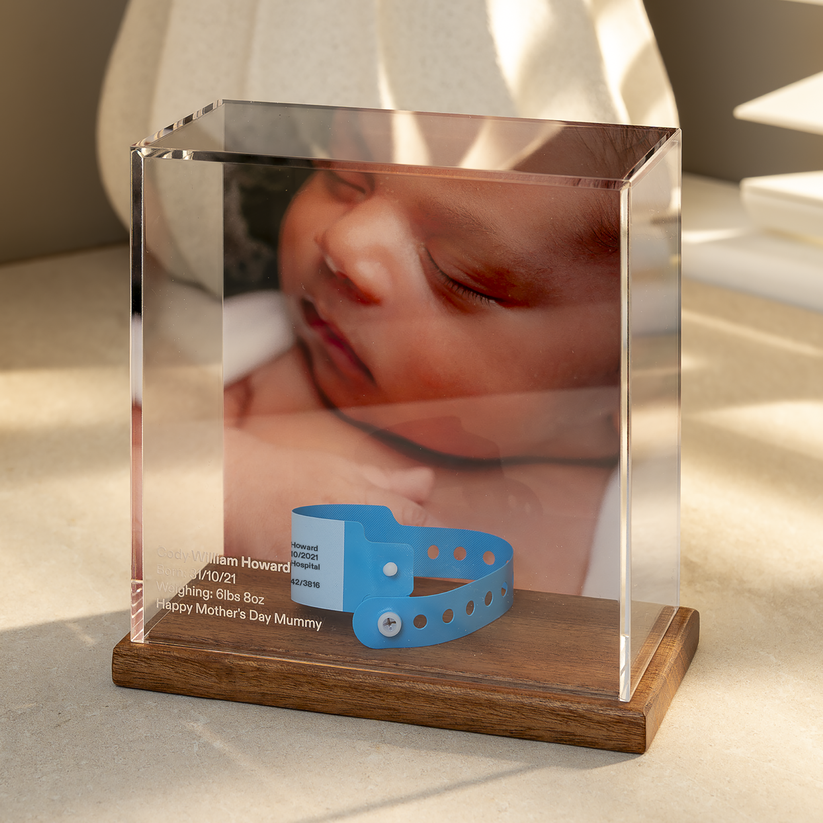 Baby Memory Case with Mahogany base displaying a photo of a baby and a blue hospital wristband, on a light surface.
