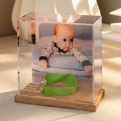 Baby Memory Case with a an Oak base displaying a photo of a baby and a hospital wristband on a light surface.