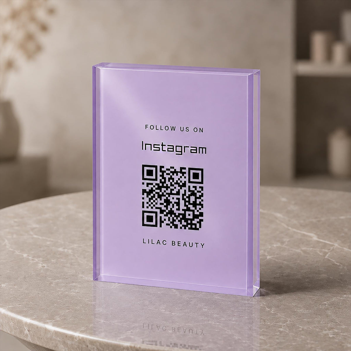 Lilac acrylic QR code sign printed with Follow us on Instagram, a QR code and a business name, standing on a round stone table.